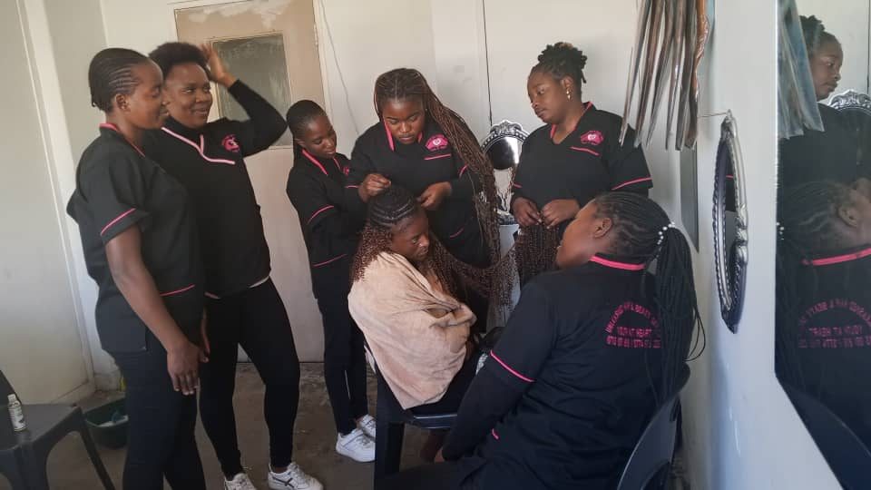 Trainees practising box braiding on a client